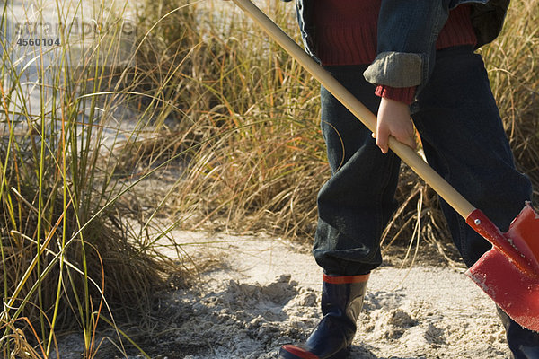 Junge beim Graben mit Schaufel im Sand