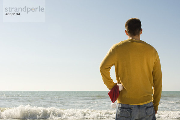 Junger Mann am Strand mit Blick auf den Strand