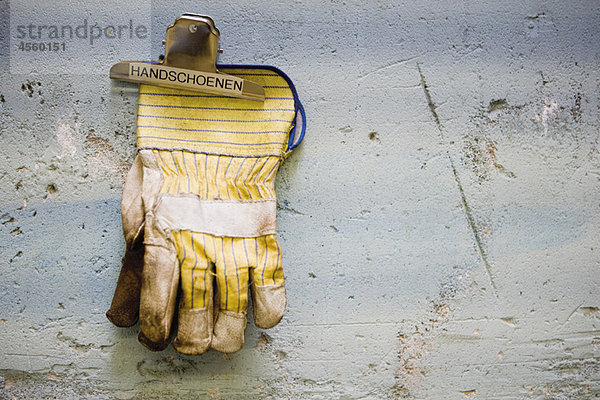 Arbeitsschutz-Handschuhe  die durch einen Binderclip an der Wand gehalten werden.