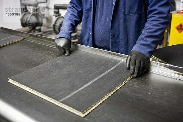 Fabrikarbeiter prüft Qualität der Teppichfliesen