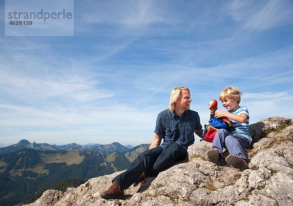 Deutschland  Bayern  Vater und Sohn (4-5 Jahre) blicken mit Karte auf den Berggipfel