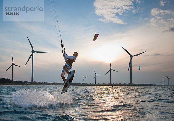 Kroatien  Zadar  Kitesurfer springen vor der Windkraftanlage