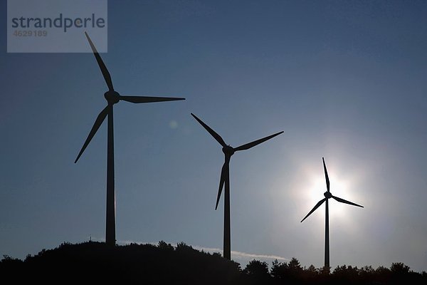 Deutschland  München  Blick auf drei Silhouetten-Windenergieanlagen bei Sonnenaufgang