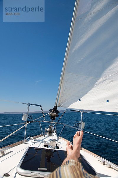 Kroatien  Zadar  Junger Mann entspannt auf dem Segelboot
