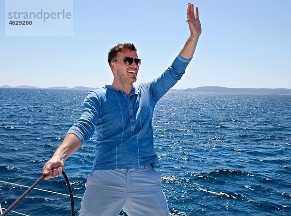 Kroatien  Zadar  Junger Mann  der vom Segelboot winkt