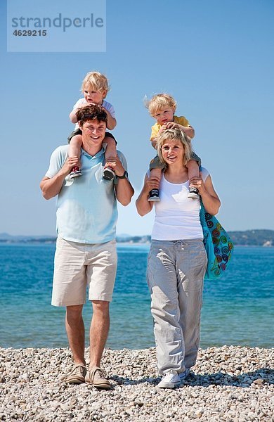 Kroatien  Zadar  Eltern mit Kindern auf der Schulter am Strand