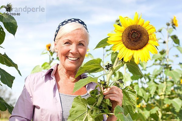 Seniorin mit Sonnenblume  lächelnd