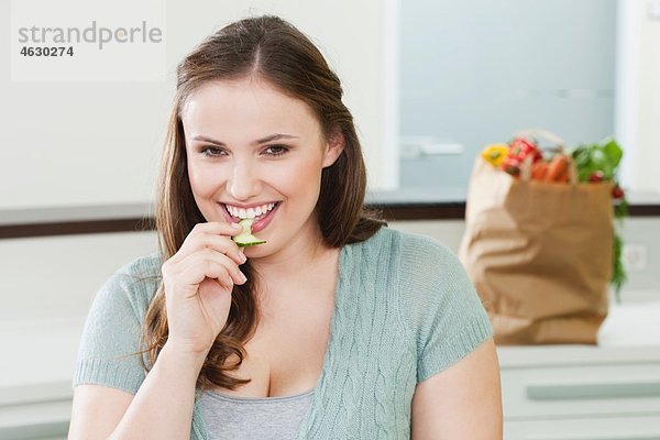 Junge Frau isst Gurkenscheibe  lächelnd  Portrait