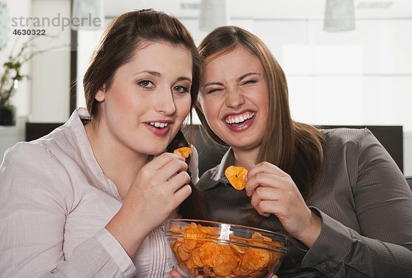 Junge Frauen essen Kartoffelchips  lächeln