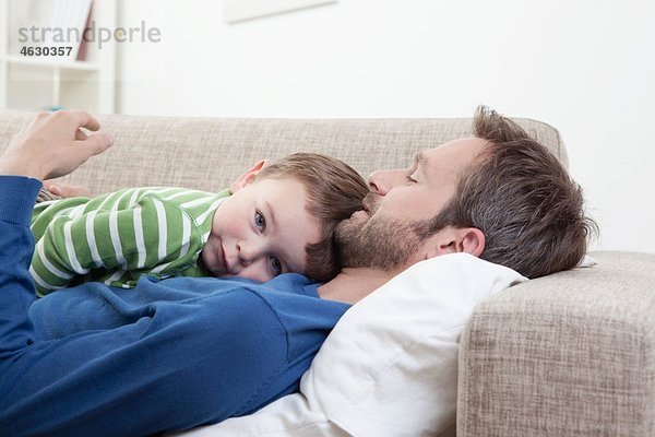Deutschland  Bayern  München  Vater und Sohn (2-3 Jahre) ruhen auf dem Sofa