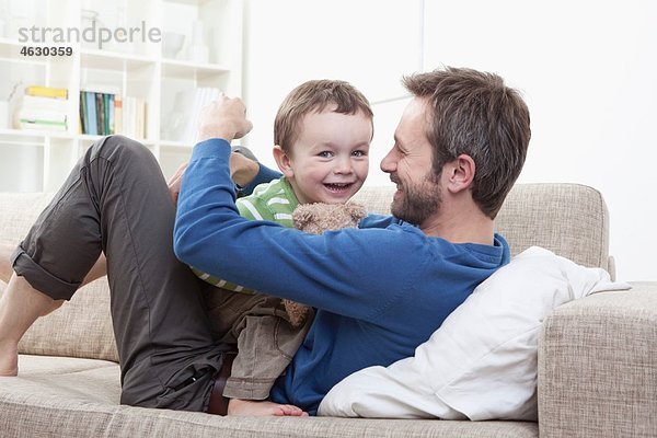 Deutschland  Bayern  München  Vater und Sohn (2-3 Jahre) mit Spaß auf dem Sofa