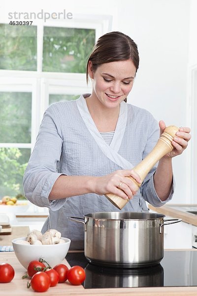 Frau bereitet Essen in der Küche zu  lächelnd