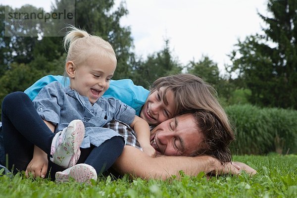 Deutschland  München  Vater mit Kindern im Garten  lächelnd