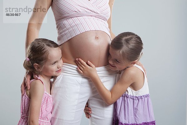 Töchter umarmen schwangere Mutter
