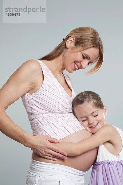 Tochter umarmt schwangere Mutter