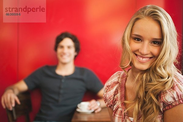 Teenagermädchen lächelt mit Mann im Hintergrund