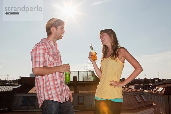 Deutschland  Bayern  München  Junges Paar im Gespräch und Biergenuss auf dem Dach