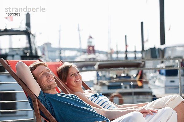 Deutschland  Hamburg  Paar im Liegestuhl entspannen  lächeln