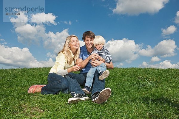 Deutschland  Köln  Familie auf Rasen sitzend  lächelnd