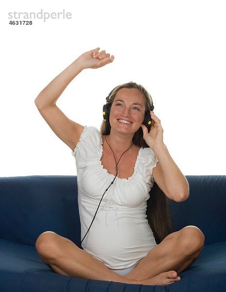 Junge schwangere Frau beim Musikhören  lächelnd