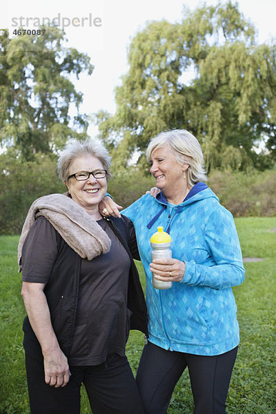 Zwei Frauen  die lächeln und Wasserflasche halten