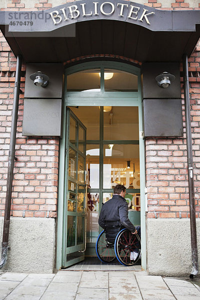 Ein Mann im Rollstuhl geht in die Bibliothek.