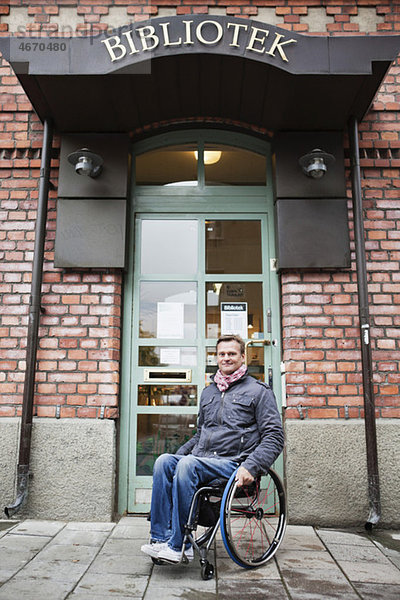 Mann im Rollstuhl sitzend vor der Bibliothek