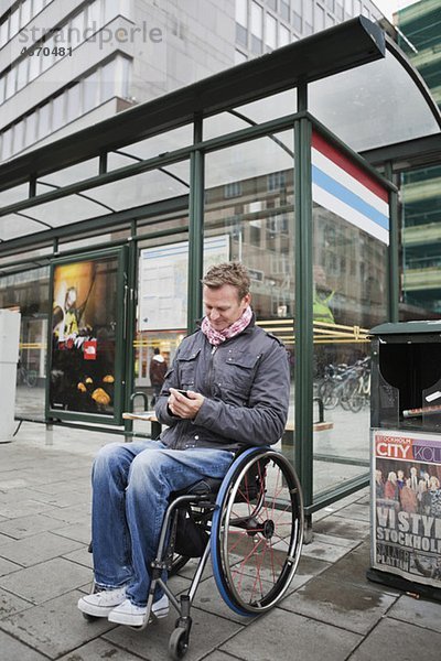 Mann im Rollstuhl wartet auf den Bus