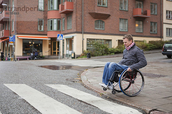 Mann im Rollstuhl überquert die Kreuzung