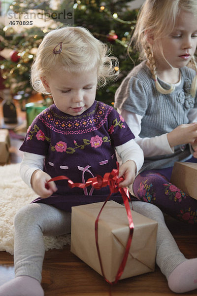 Zwei Mädchen öffnen Weihnachtsgeschenke