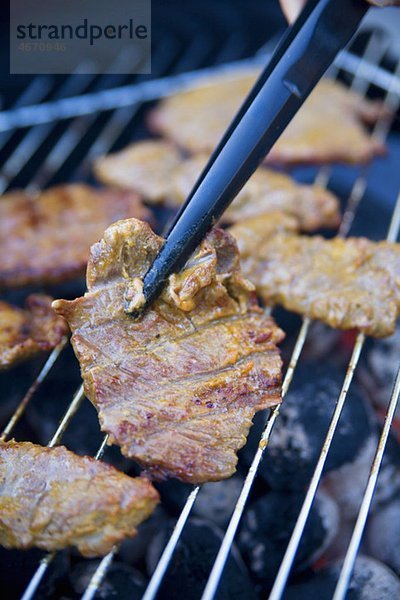 Fleisch auf dem Grill wenden