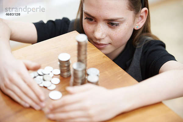 Mädchen schaut auf einen Haufen Geld.