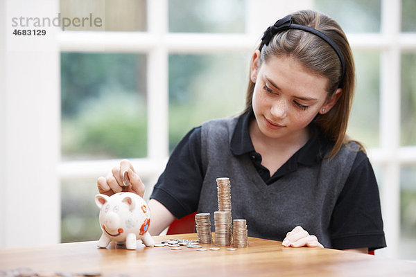 Mädchen mit Sparschwein und Haufen Geld