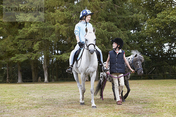 Zwei Mädchen reiten auf Ponys.