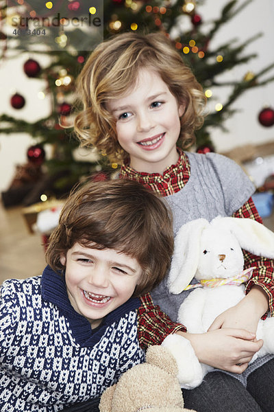 Kinder lachen vor dem Weihnachtsbaum