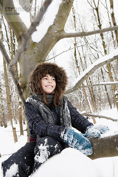 Mädchen unter einem verschneiten Baum sitzend