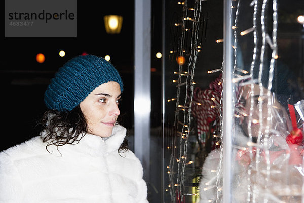 Frau bei Nacht mit Blick auf das Schaufenster