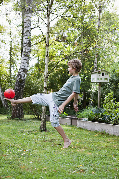 Junge spielt mit Ball im Garten