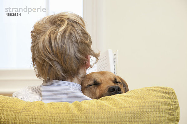 Junge liest beim Kuscheln des Hundes