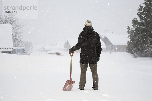 Mann im Schnee stehend mit Schaufel