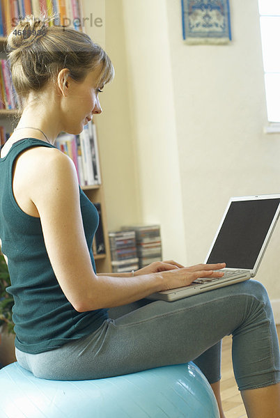 Frau auf Laptop sitzend auf Schweizer Ball