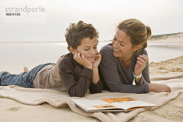 Mutter und Sohn beim Lesen am Strand