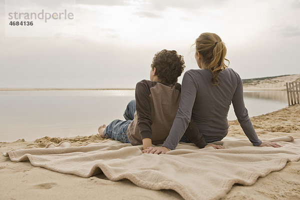 Mutter und Sohn sitzen am Strand