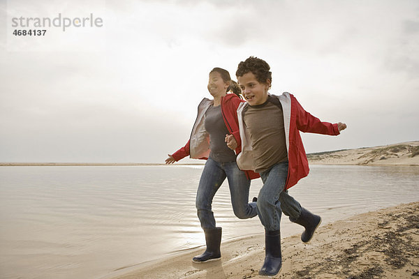 Mutter und Sohn laufen zusammen am Strand.