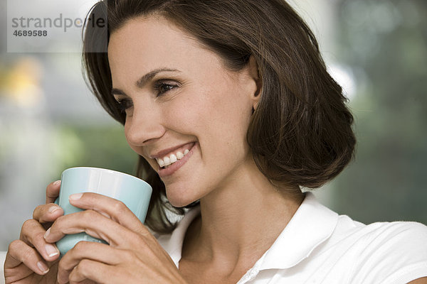 Lächelnde Frau hält eine Kaffeetasse