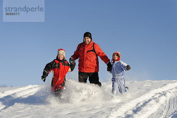 Kinder mit Vater im Schnee
