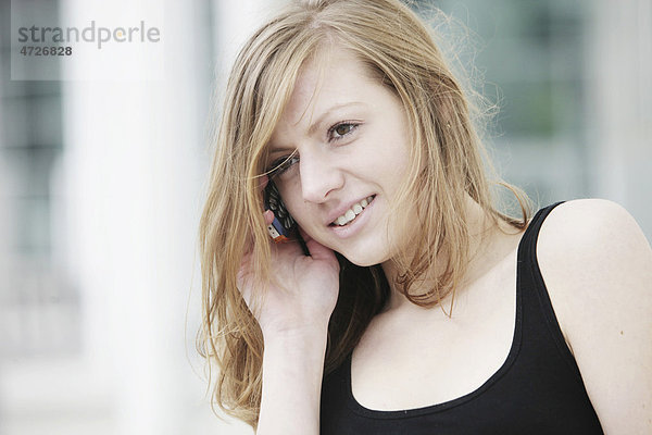Junge Frau telefoniert mit dem Handy  lächelnd