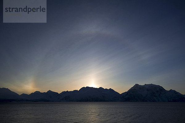 Ein 22_-Ring Halo  ein atmosphärischer Lichteffekt  über den Bergen von Troms  Norwegen  Europa