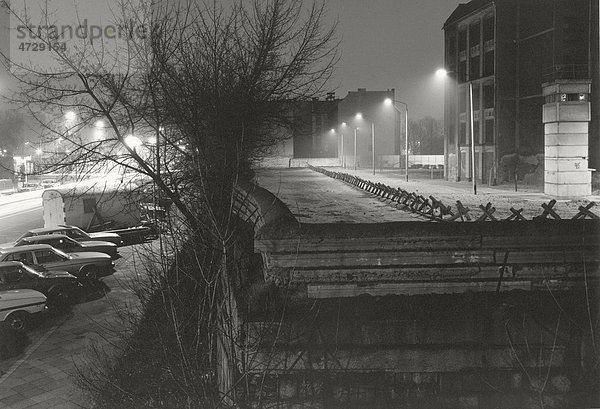 Blick über die Berliner Mauer 1985  beleuchteter Todesstreifen mit Wachturm und unbewohntem Häuserblock im Ostteil Berlins  Berlin  Deutschland  Europa