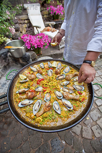 Ein Koch bereitet eine Paella  spanisches Reisgericht  zu  Zugabe von Zitrone  Serie  Nr. 6